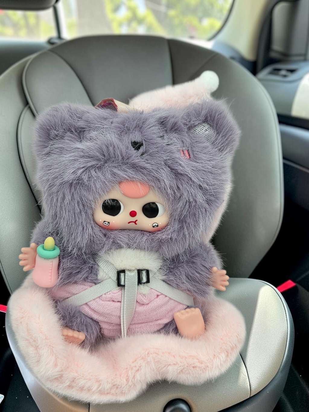 Momof2boyz Shop Baby Three BB3 vehicle mounted baby figure in a grey fuzzy animal hood with a pink outfit and bottle.