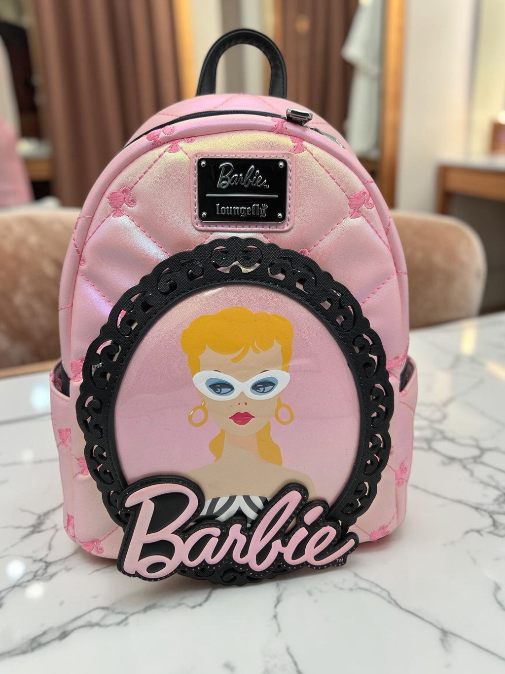 Momof2boyz Shop iridescent pink quilted Barbie mini backpack with a black filigree portrait frame and logo plaque.