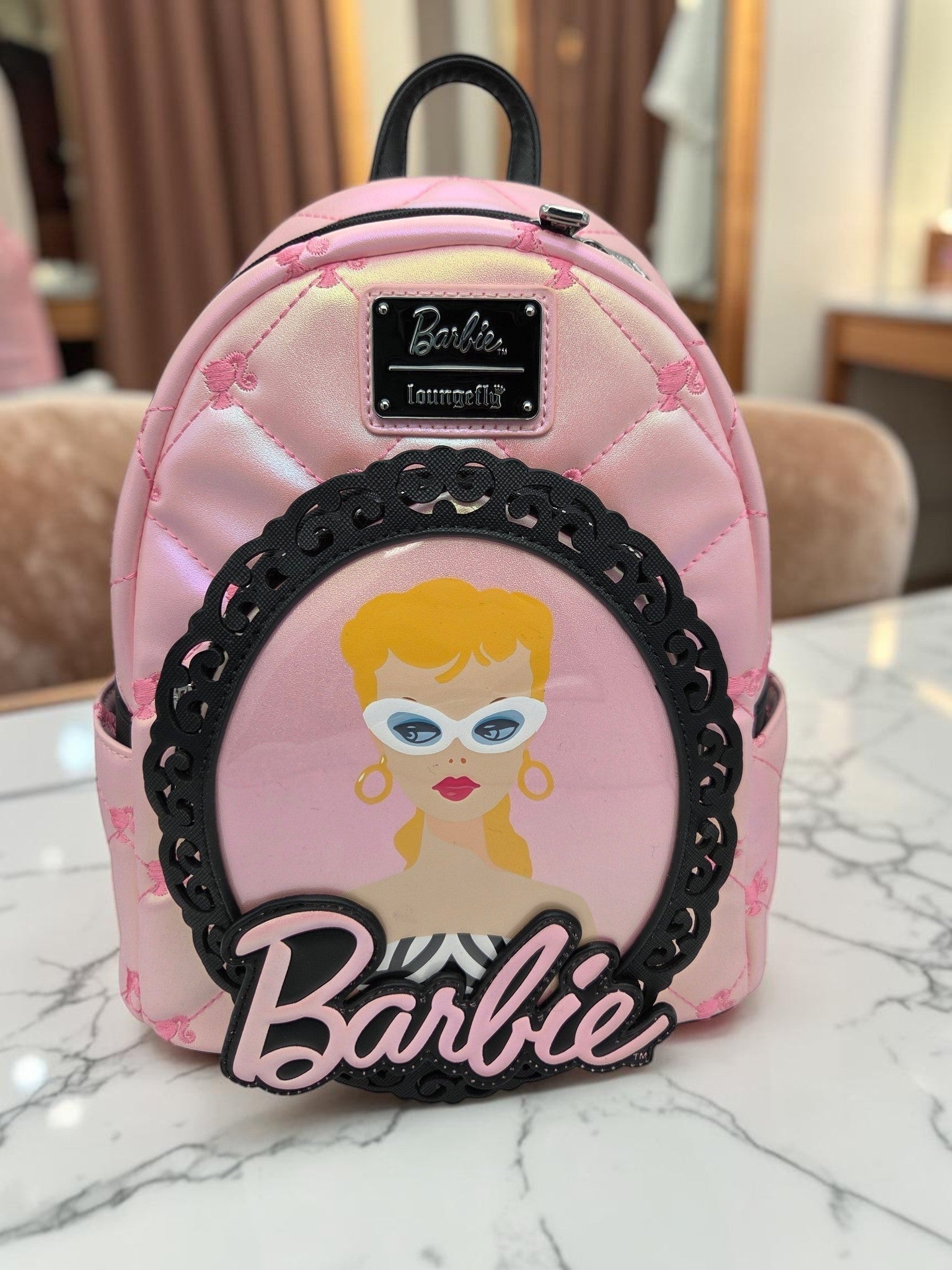 Momof2boyz Shop iridescent pink quilted Barbie mini backpack with a black filigree portrait frame and logo plaque.