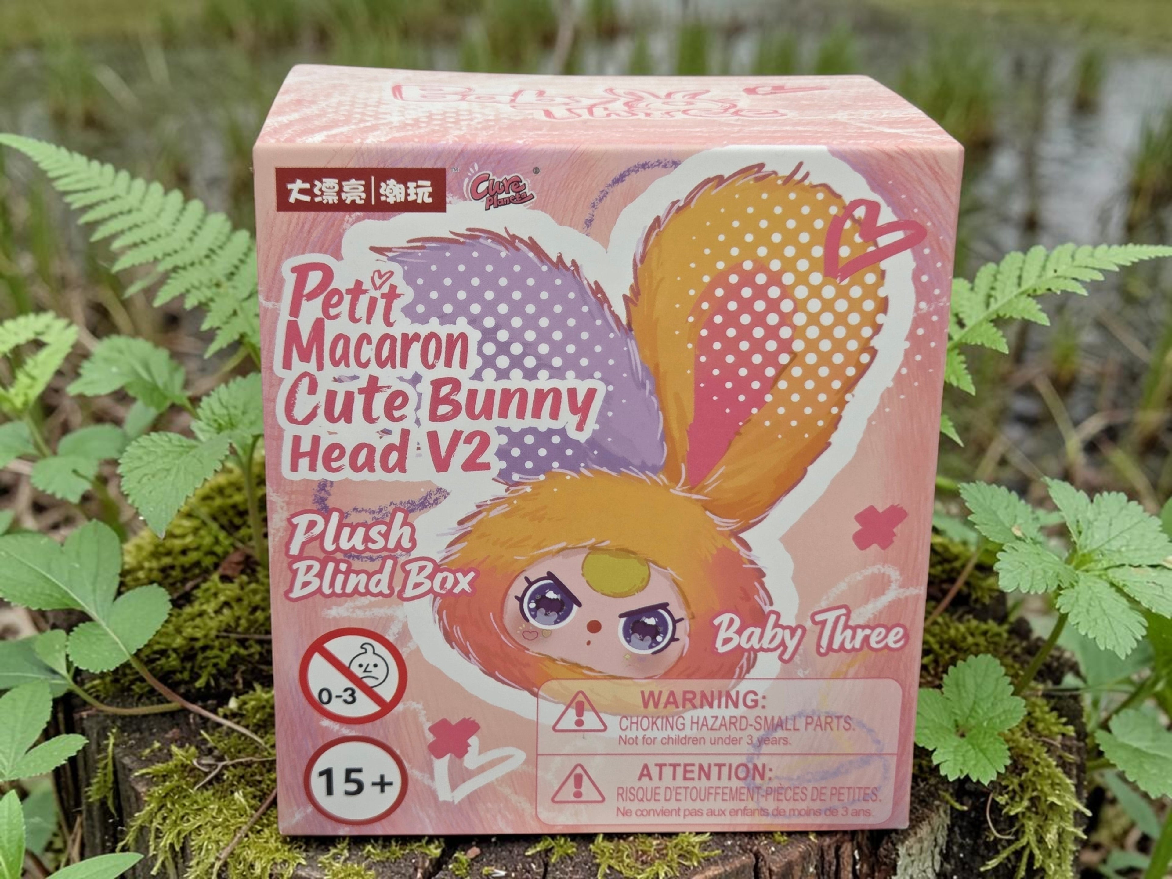Momof2boyz Shop Baby Three Petit Macaron Cute Bunny Head V2 plush blind box with purple and orange ears.