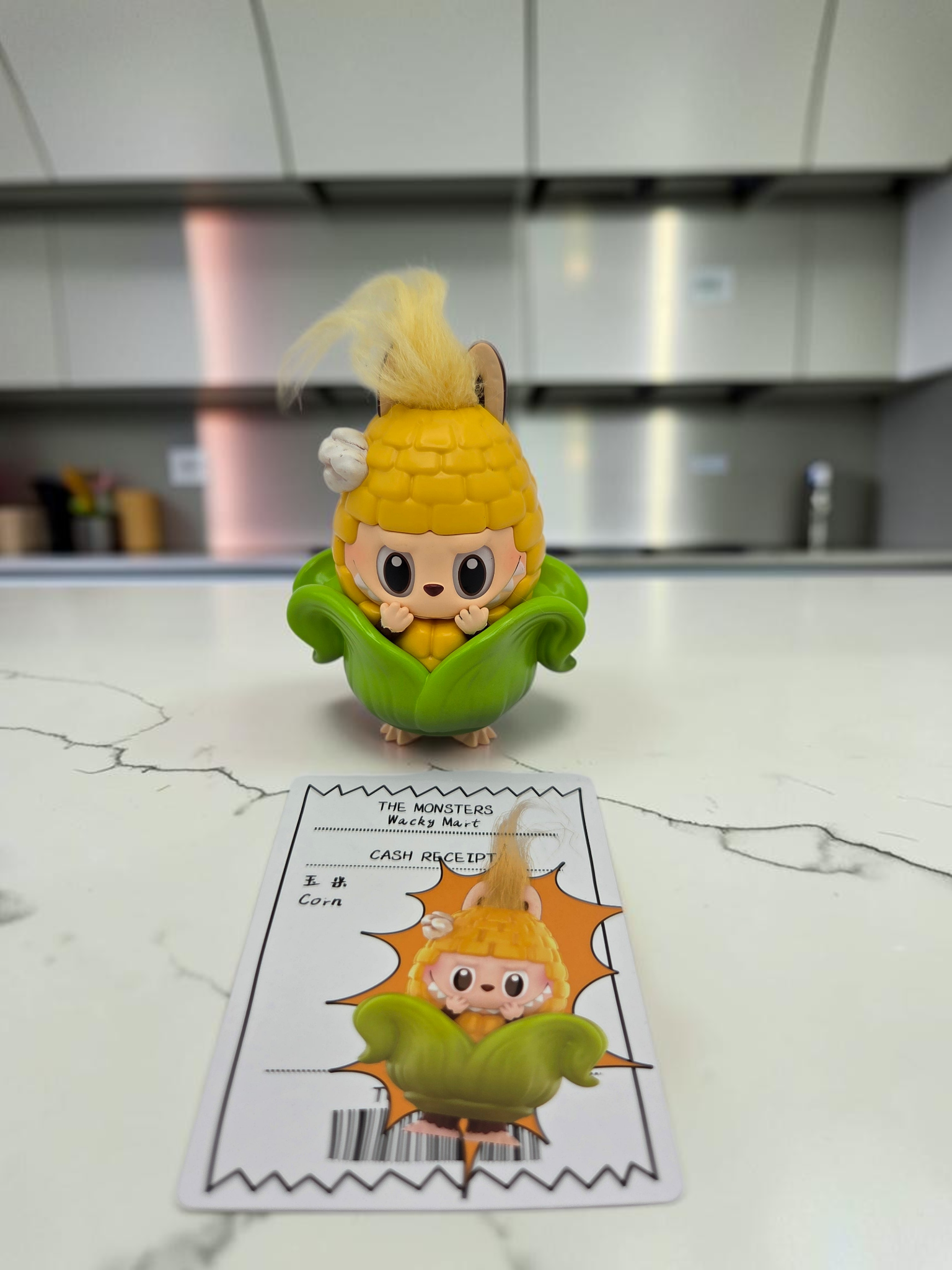 Momof2boyz Shop The Monster's Wacky Mart corn character figure with blonde hair and green leaves on a kitchen counter.
