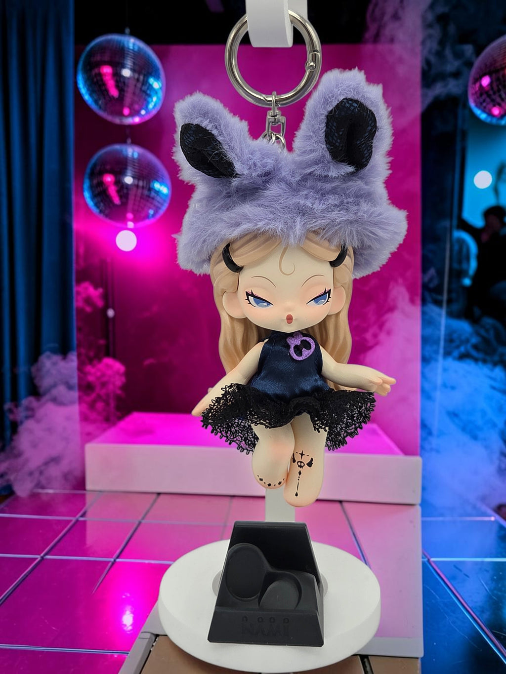 Momof2boyz Shop Dodo Nami Midnight Disco collectible keychain featuring a doll in a purple fuzzy hat and black dress