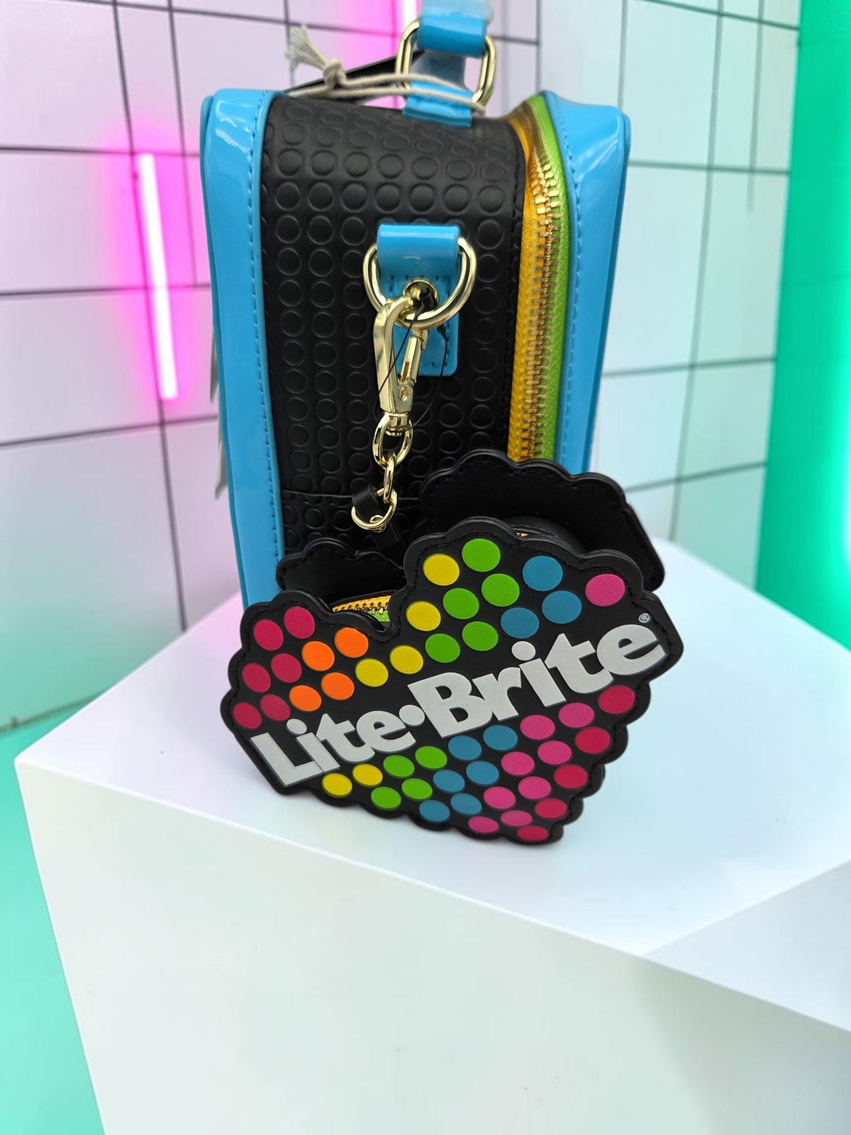 Momof2boyz Shop Lite-Brite crossbody bag with a black textured panel and a heart-shaped colorful coin purse accessory.