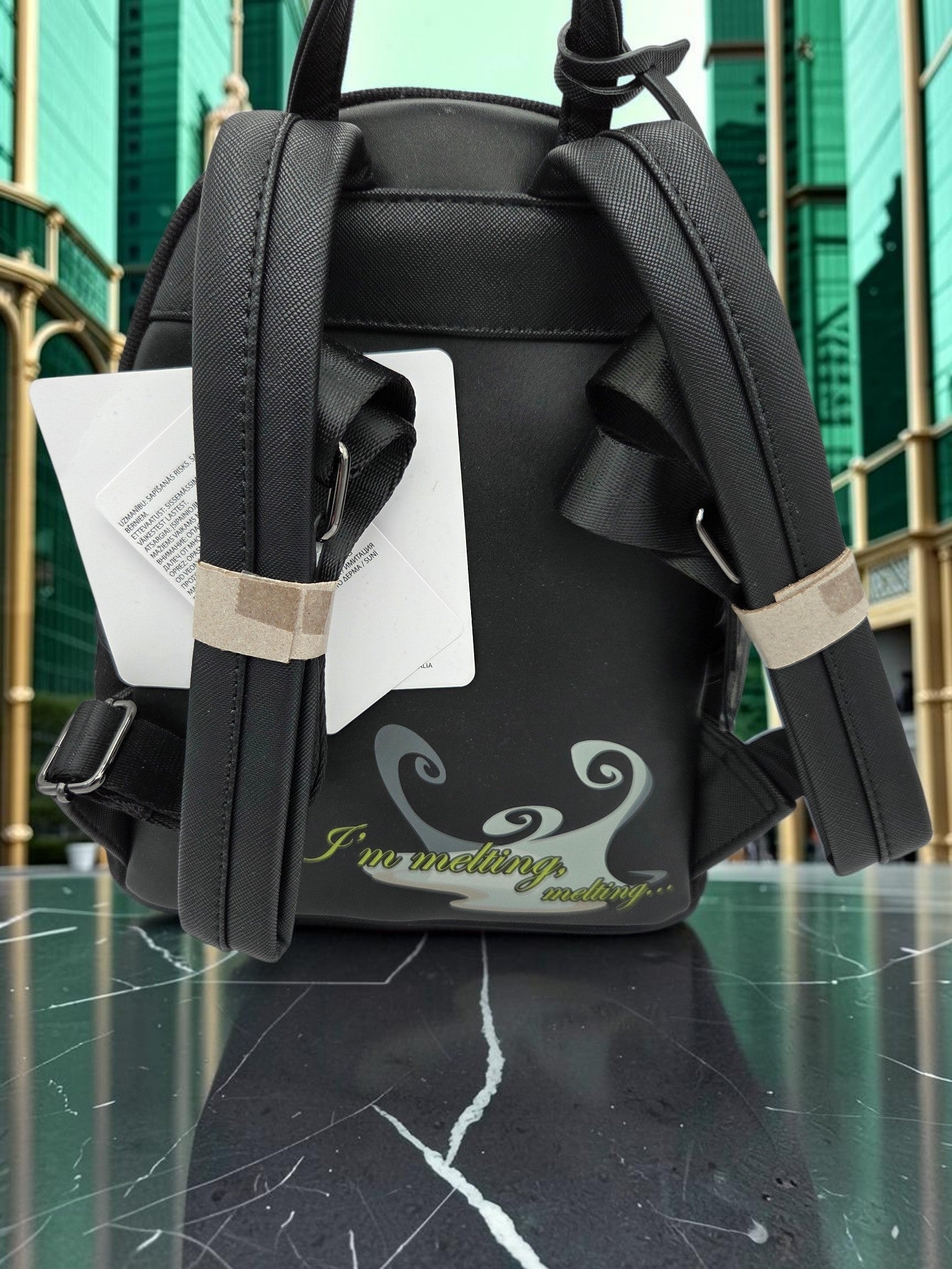 Momof2boyz Shop Loungefly Wizard of Oz Wicked Witch mini backpack back view with I'm melting quote and black straps
