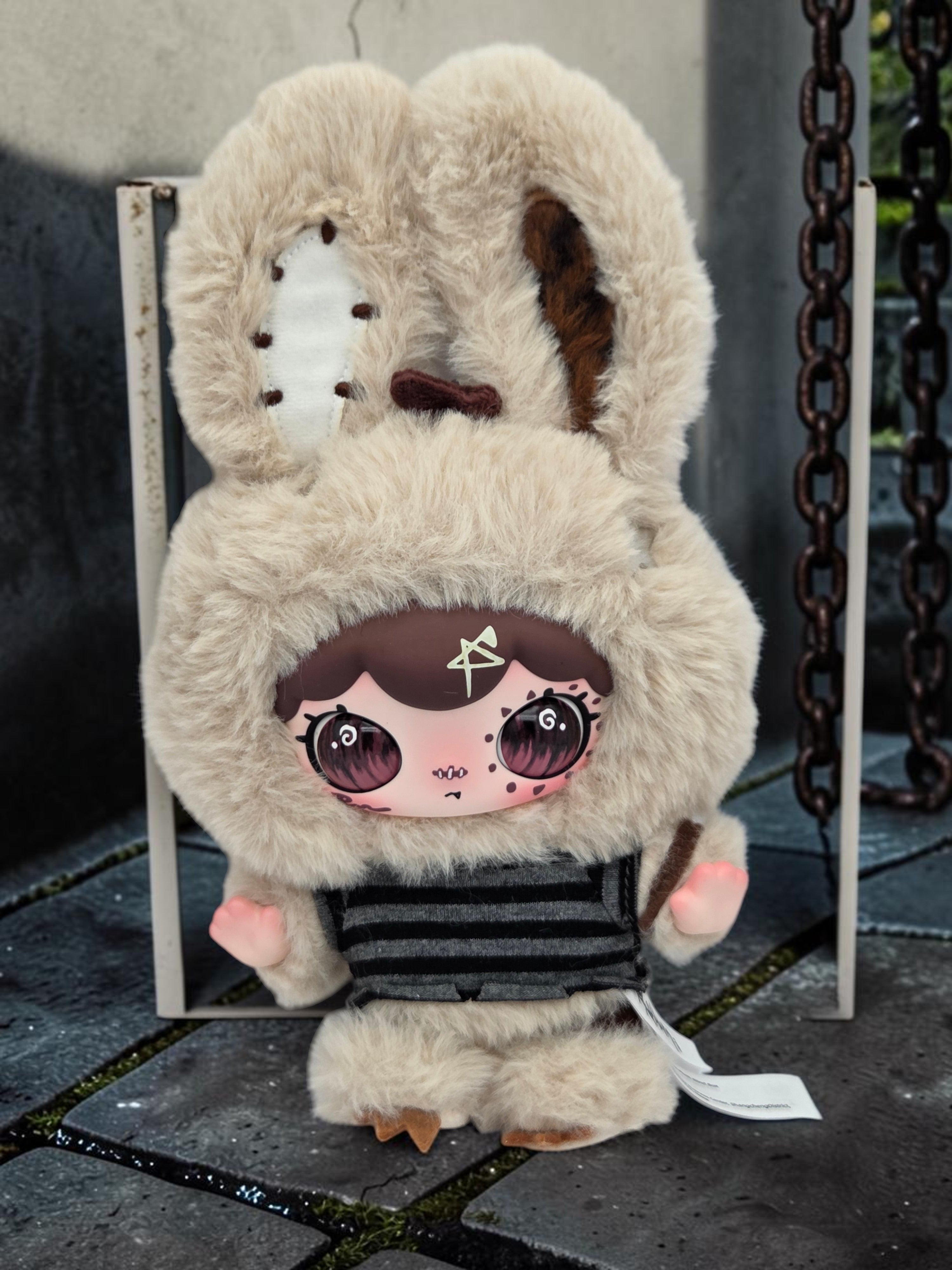 Momof2boyz Shop Lulumi The Seventh Pain plush toy with beige faux fur, striped shirt, and large expressive eyes.