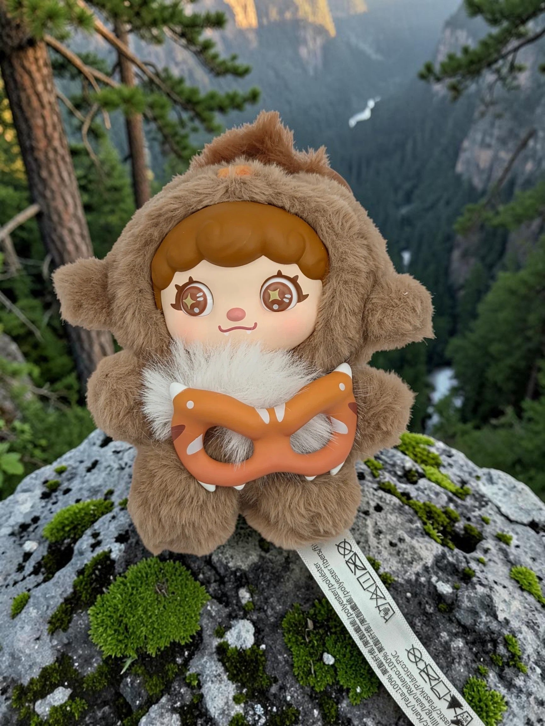 Momof2boyz Shop Mochi Little Monster plush keychain featuring a brown bear character with a removable mask on a rock