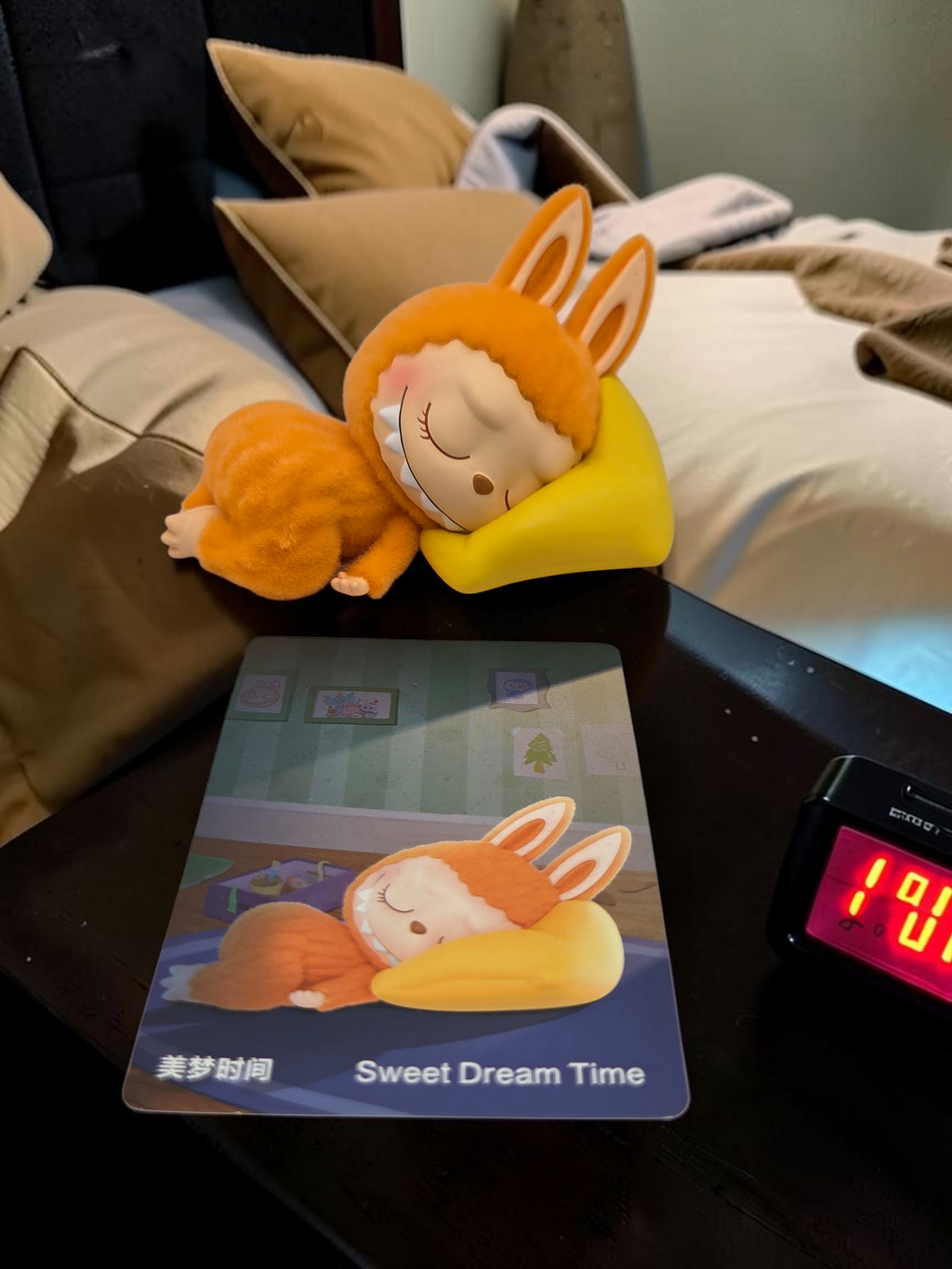 Momof2boyz Shop The Monster's 1:00 am collectible figure of a sleeping orange rabbit character on a yellow pillow.