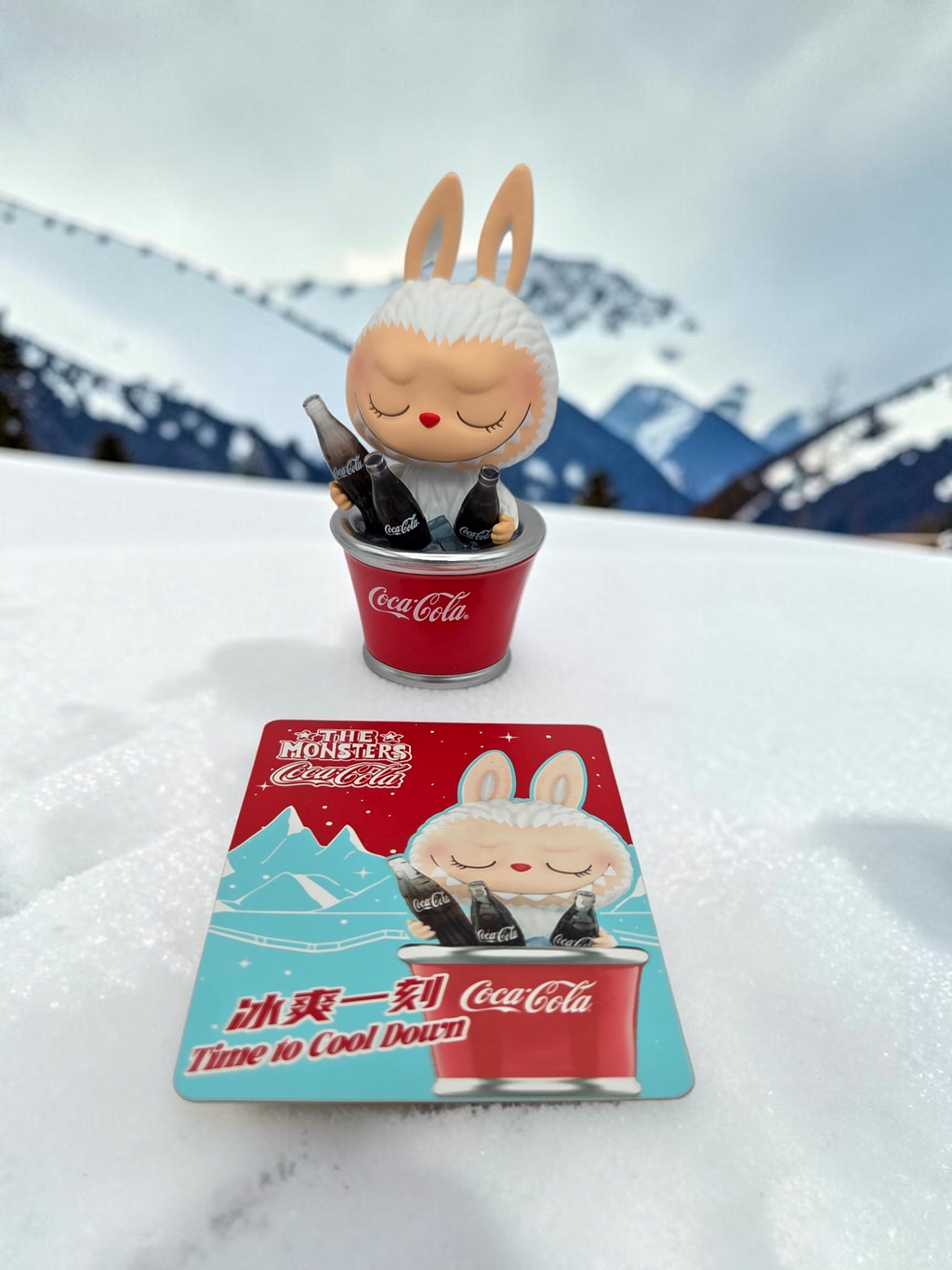 Momof2boyz Shop The Monster's Coca-Cola figure in a bucket with matching collector card on snowy mountain background