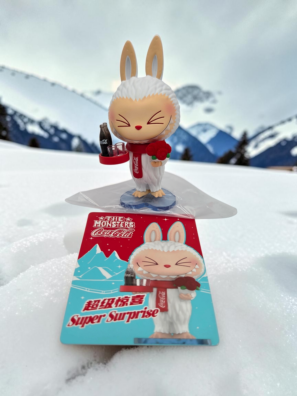 Momof2boyz Shop The Monster's Coca-Cola figure featuring a white rabbit character with a red scarf in the snow.