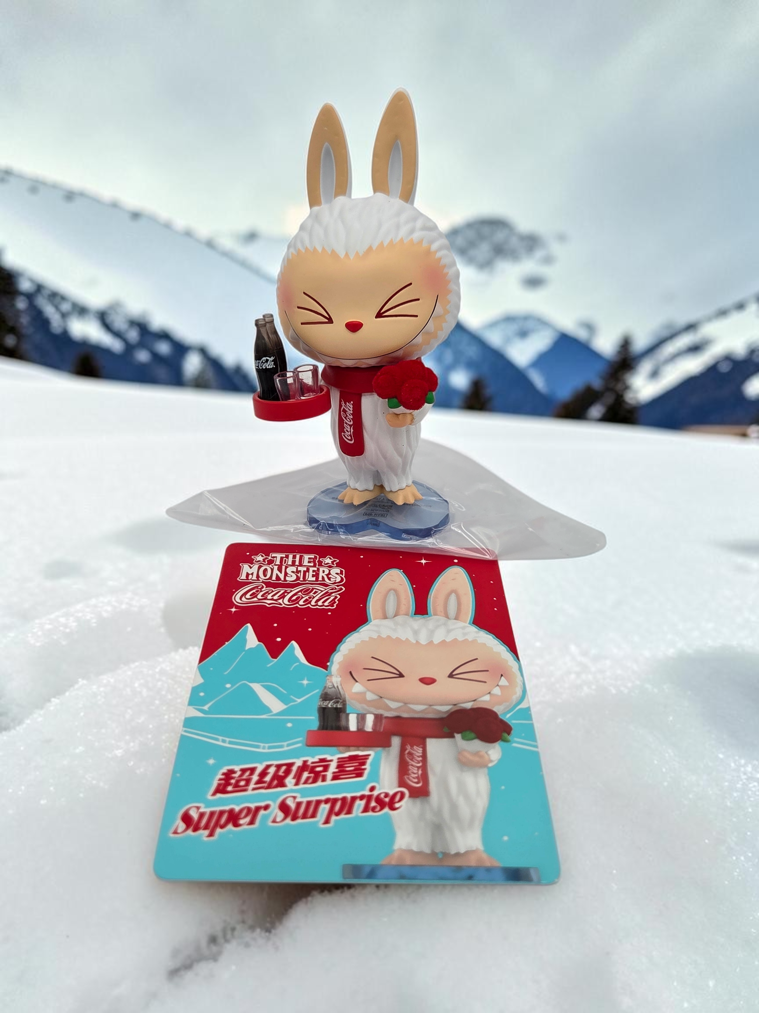 Momof2boyz Shop The Monster's Coca-Cola figure featuring a white rabbit character with a red scarf in the snow.