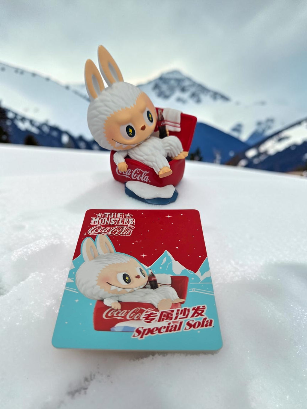 Momof2boyz Shop The Monster's Coca-Cola figure with white bunny character sitting on a red sofa in snowy mountains