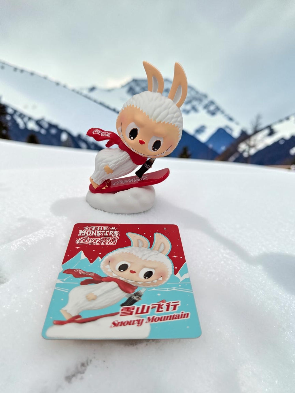 Momof2boyz Shop The Monster's Coca-Cola Snowy Mountain rabbit figure with matching collector card on snowy terrain.