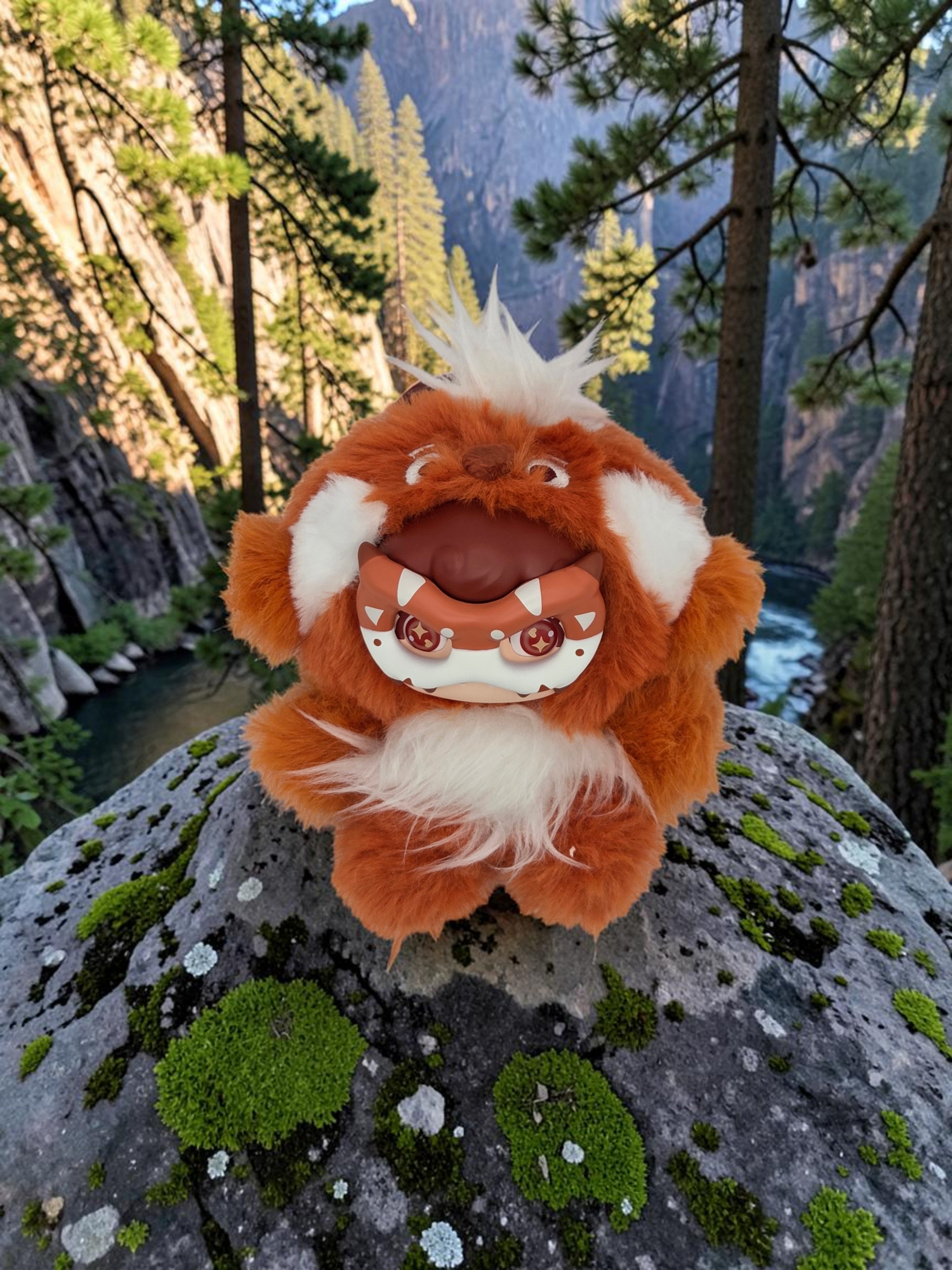 Momof2boyz Shop Mochi Little Monster Sunny Red Panda plush keychain with a removable mask on a mossy rock in nature.