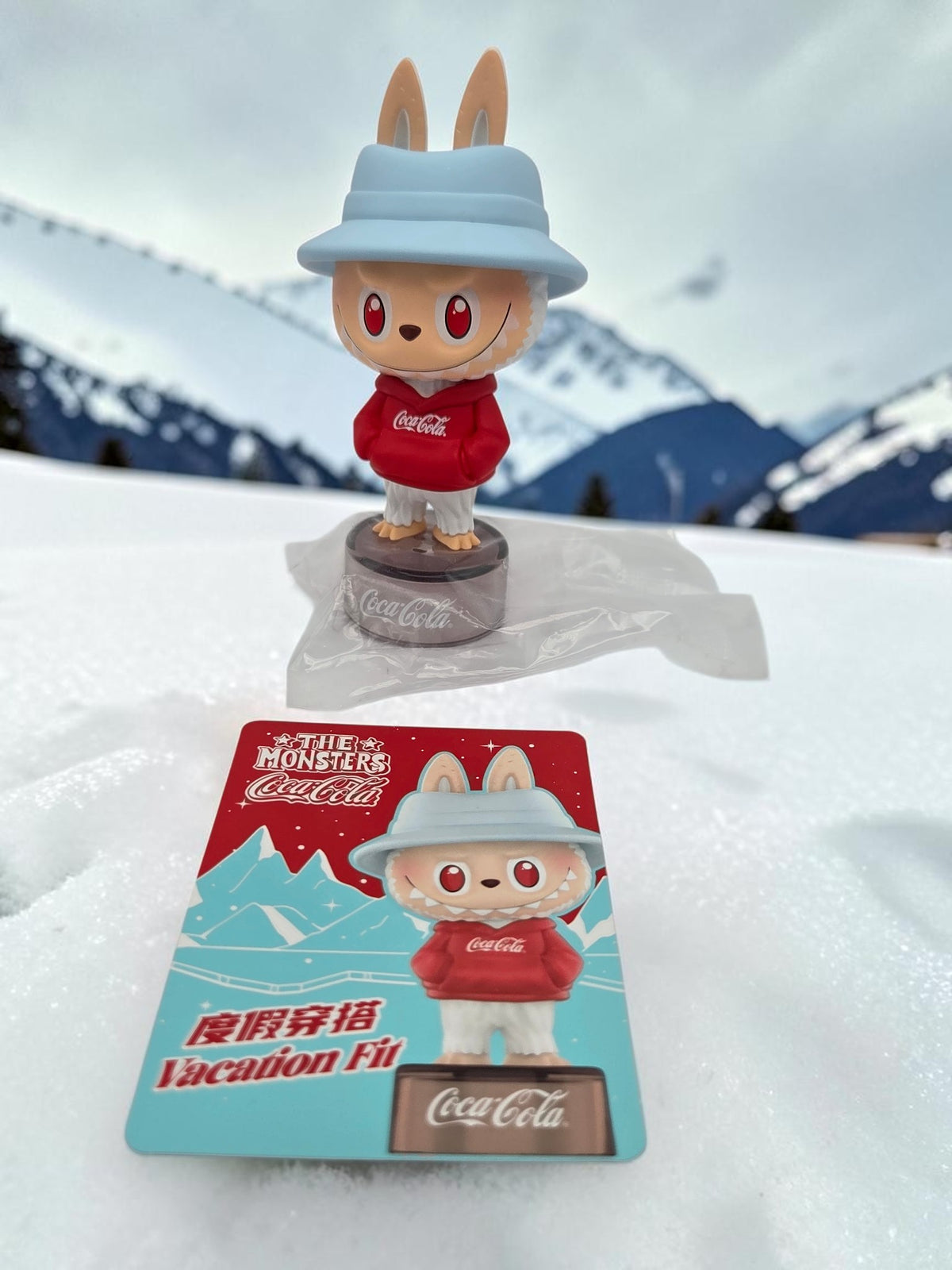 Momof2boyz Shop The Monster's Coca-Cola Vacation Fit figure wearing a red hoodie and blue hat with matching card.